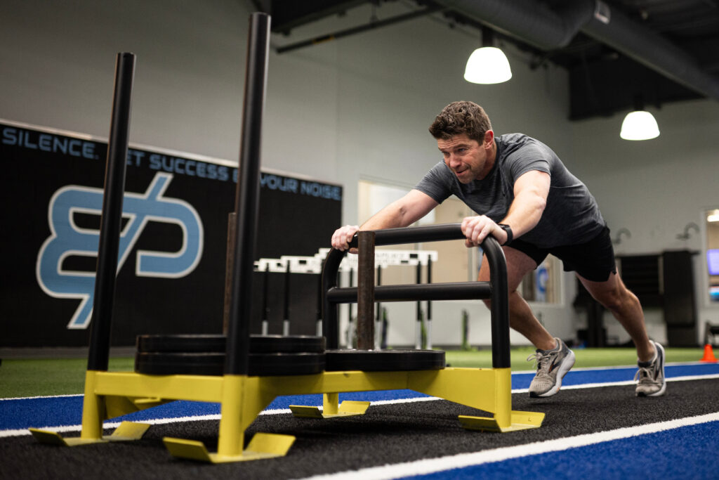 How to Get Faster for Sports: A Complete Training Guide 2 Adult male athlete pushing sled to train speed