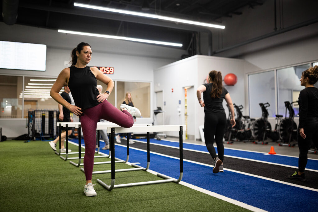 How to Get Faster for Sports: A Complete Training Guide 3 Female athlete using hurdles to improve hip mobility in a group training session